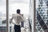 British executive talking on smart phone in office with view
