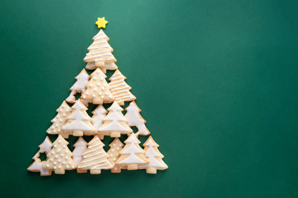 Christmas tree made from christmas tree shaped cookies on green background with copy space