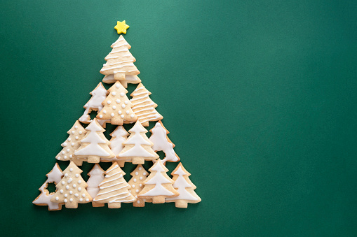 Christmas tree made from christmas tree shaped cookies on green background with copy space for text