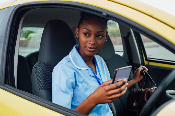 Arriving at the Patients Home Nurse arriving at a patient's home in the North East of England. She is sitting in her car using her mobile phone. Travel Nurse stock pictures, royalty-free photos & images