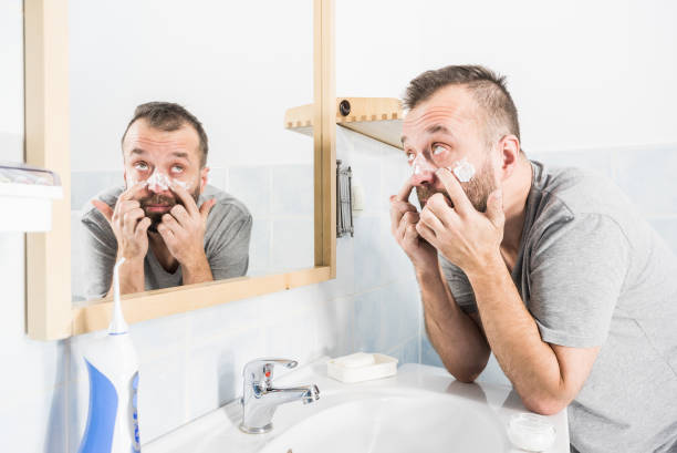 istock Man applying moisturizer cream in bathroom 1355254299