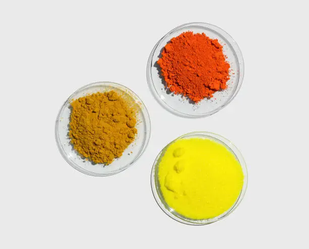 Photo of Lead (II,IV) oxide, Potassium Chromate and Organic Curcuma Powder in Chemical Watch Glass. Closeup chemical ingredient on white laboratory table. Top View