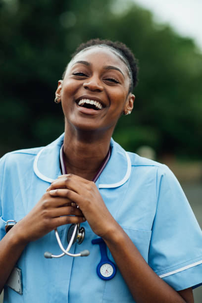 Portrait of a nurse dressed in her scrubs uniform in the North East of England. She is laughing while looking at the camera.