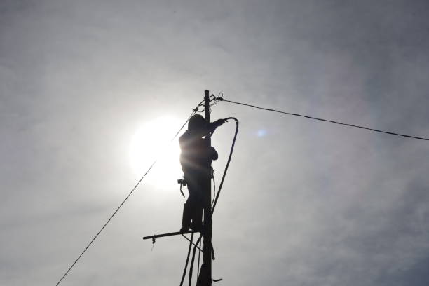 istock workers climb power poles to connect power lines 1355255007