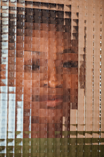Close up of a woman standing behind a frosted glass effect