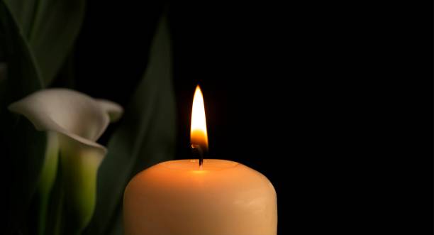 istock Candle burning flame in the darkness and arum lilies 1355255374