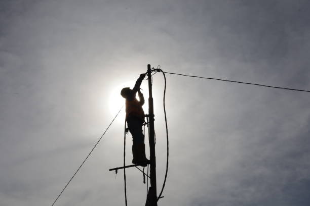 istock workers climb power poles to connect power lines 1355255468