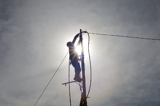 workers climb power poles to connect power lines