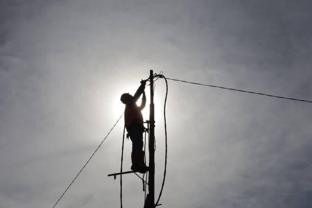 istock workers climb power poles to connect power lines 1355255719
