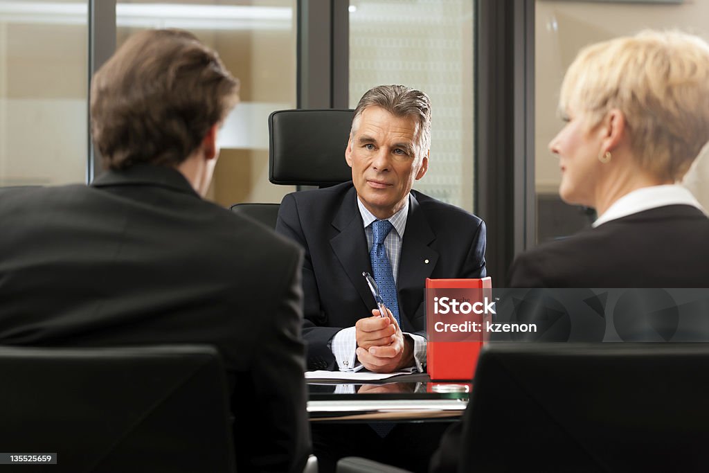 Lawyer or notary with clients in his office Mature lawyer or notary with clients in his office in a meeting Lawyer Stock Photo