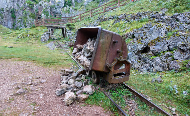 istock Old mine cart overturned a load on an abandoned mine track in the mountain 1355259646