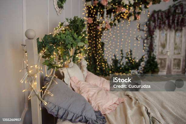 Vintage Photo Zone A White Bed And A Decorative Tree Decorated With Plants And Light Bulbs Stock Photo - Download Image Now