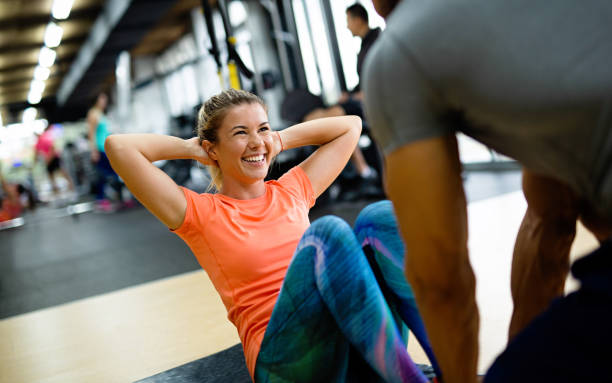Fit happy woman with her personal fitness trainer in the gym exercising with dumbbells stock photo