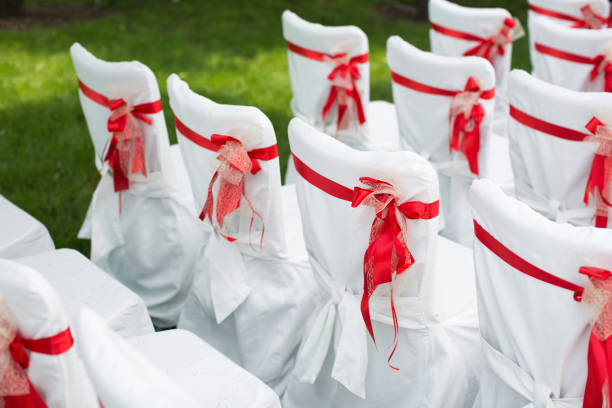 istock Wedding ceremony outdoors. White chairs with red ribbon. 1355262252
