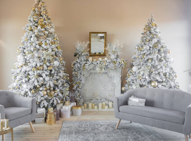 istock Beautiful stylish decorated interior two Christmas trees with a fireplace and gray sofas and gifts 1355262553