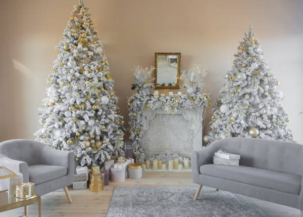 istock Beautiful stylish decorated interior two Christmas trees with a fireplace and gray sofas and gifts 1355263339
