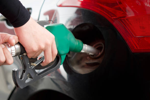 nahaufnahme der grünen gaspumpendüse. tankstellenarbeiter tankt schwarzes auto. - gasohol stock-fotos und bilder