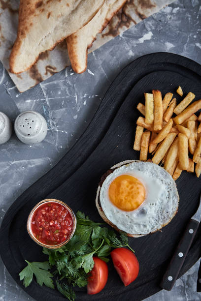 istock Beef steak with egg and salad from greens and vegetables. Gray background, table setting, fine dining 1355266156