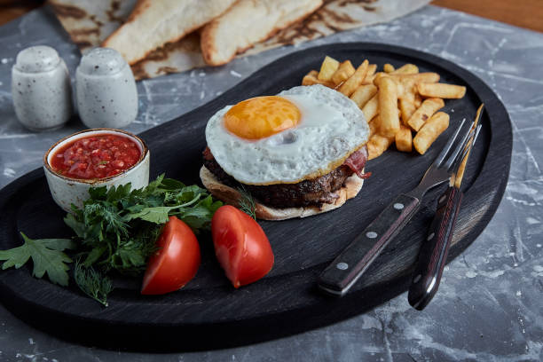 istock Beef steak with egg and salad from greens and vegetables. Gray background, table setting, fine dining 1355266180