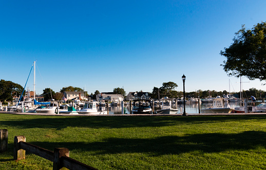 Babylon, New York, USA - 7 September 2021: Boats docked in a marina in Babylon Village with blue sky above on an early September morning.