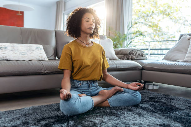 自宅のリビングルームの床に座って蓮の位置でリラックスした成熟した女性。 - yoga business women living room ストックフォトと画像