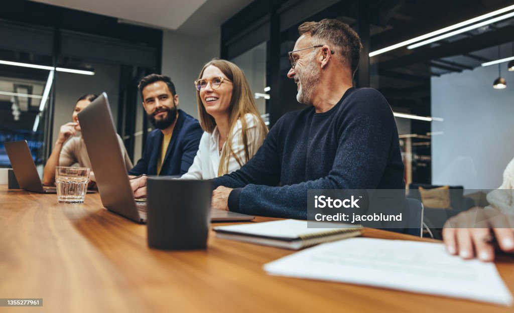 Successful group of businesspeople having a briefing Successful group of businesspeople having a briefing in a boardroom. Happy businesspeople smiling while working together in a modern workplace. Diverse business colleagues collaborating on a project. Office Stock Photo