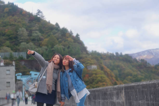 istock Young Asian students relaxing beside autumn lake 1355277985