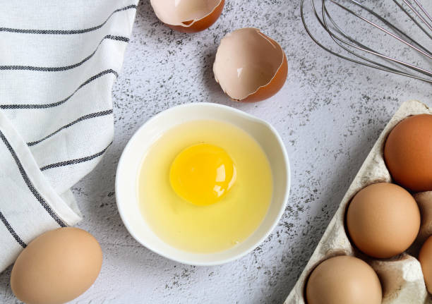 istock Raw eggs and whisk on a wooden background, top view. Cooking baking ingredients eggs, whisk and kitchen textiles on a wooden background. Pie or cake recipe, breakfast concept, top view. 1355278610
