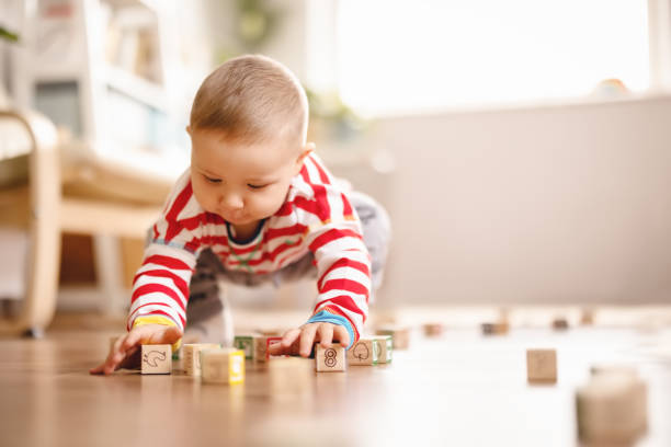 pequeño bebé jugando con juguetes en el suelo en el interior. - cube baby child block fotografías e imágenes de stock