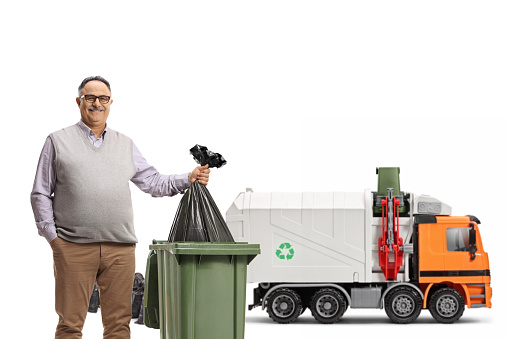 Garbage truck and a mature man throwing a plastic bag in a bin isolated on white background