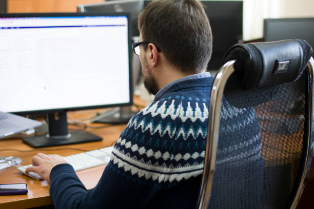 istock Young programmer typing on a freestanding white keyboard on a wooden table in front of two monitors 1355287718