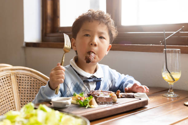istock A little boy eating steak in a restaurant 1355289253
