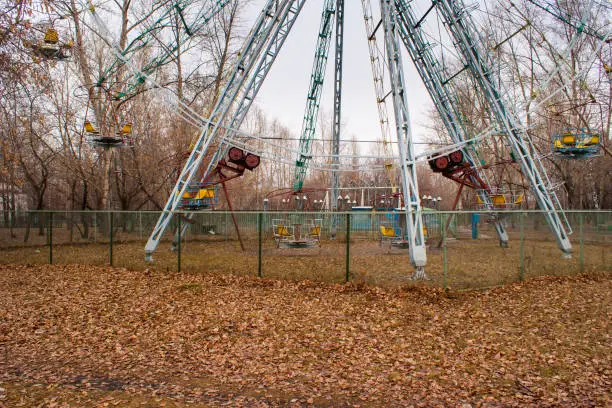 empty ferris wheel in amusement park behind mesh fence