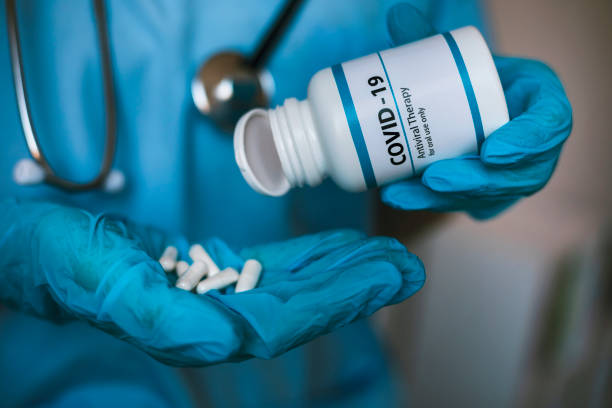Infectious doctor holding COVID 19 antiviral drug Infectious doctor wearing protective workwear holding COVID 19 antiviral drug. Coronavirus pandemic. antiviral drug stock pictures, royalty-free photos & images