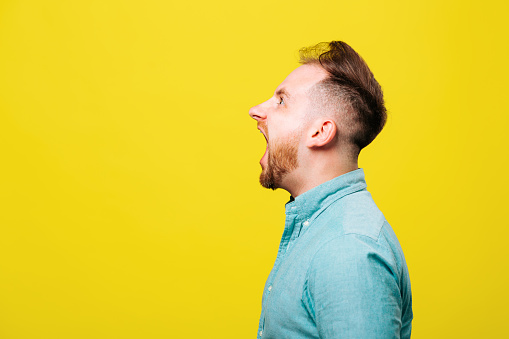 side view of a Shocked man while screaming isolated on yellow background. studio shot