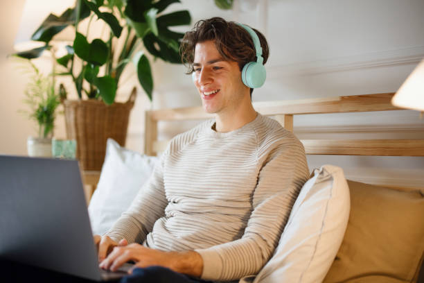 istock Young man lying in bed and using laptop for work and video conference call 1355296017