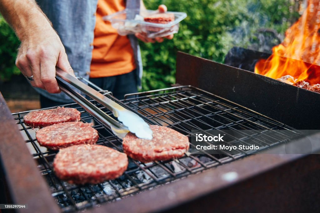 Shot of a man grilling burgers during a barbecue It's a good day for some burgers Barbecue Grill Stock Photo