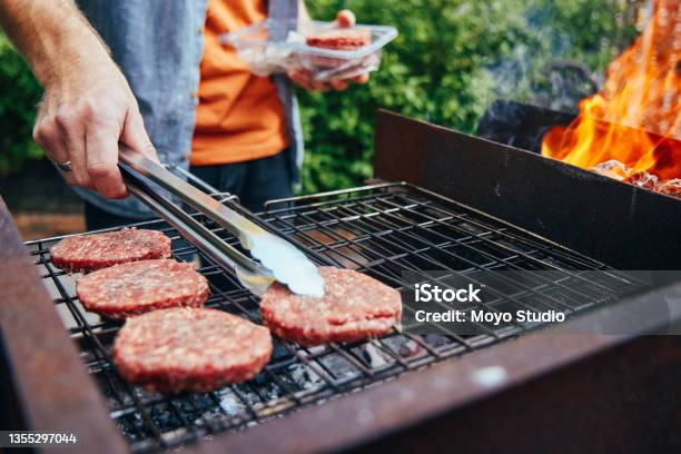 Shot Of A Man Grilling Burgers During A Barbecue Stock Photo - Download Image Now - Barbecue Grill, Barbecue - Social Gathering, Barbecue - Meal