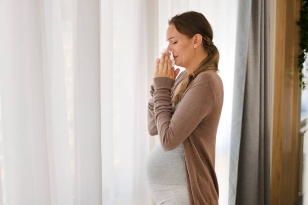 Young pregnant woman blowing her nose stock photo