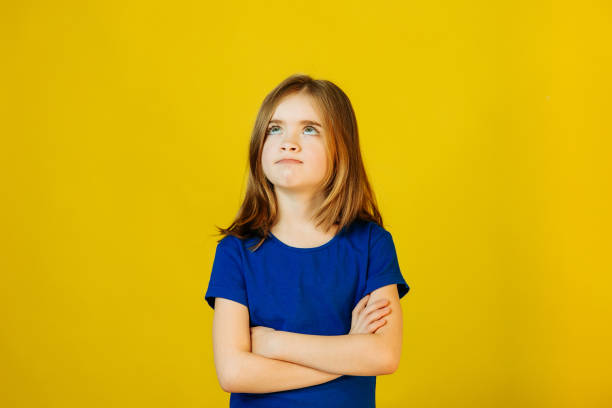 istock Upset child with hands crossed on yellow background in studio 1355297323