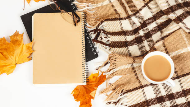 Cozy home table with a beige plaid, coffee cup, notepad, on a white background. Autumn fall or winter holidays concept. Concept of hot drinks in autumn