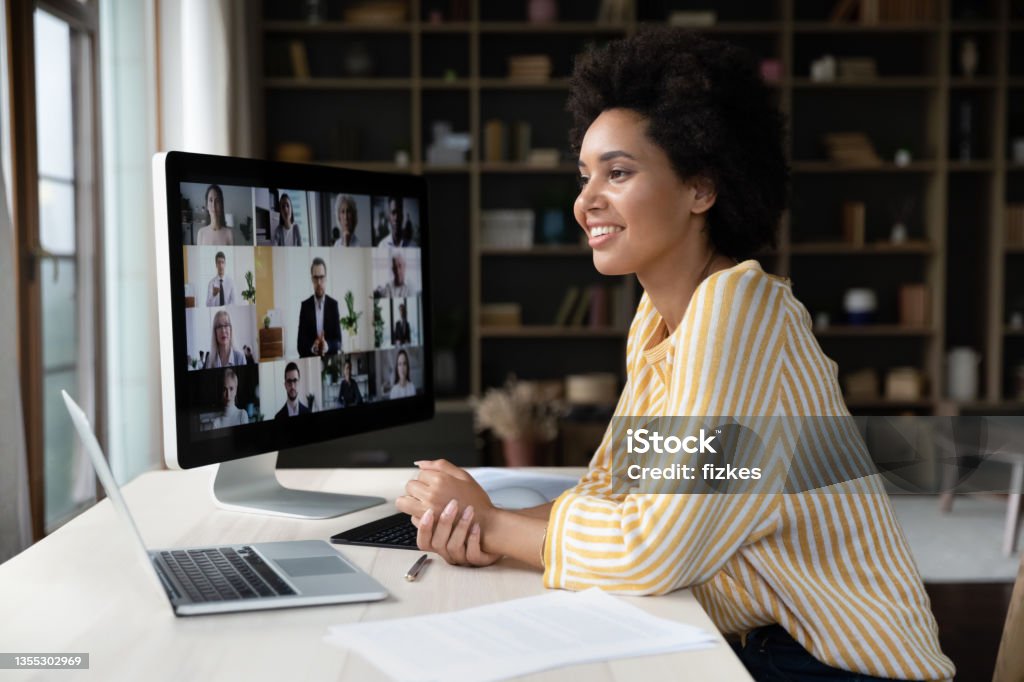 Happy African American employee talking on video conference call Happy African American remote employee talking on video conference call to colleagues, sitting at computer monitor, speaking to audience, attending virtual business meeting, negotiations, seminar Web Conference Stock Photo