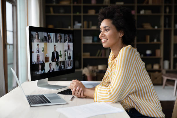 Happy African American employee talking on video conference call Happy African American remote employee talking on video conference call to colleagues, sitting at computer monitor, speaking to audience, attending virtual business meeting, negotiations, seminar online training stock pictures, royalty-free photos & images