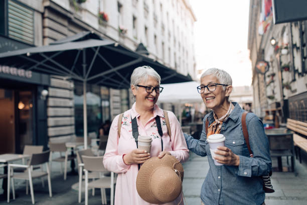 istock Two senior friends on a journey drinking coffee and enjoying their walk 1355303292