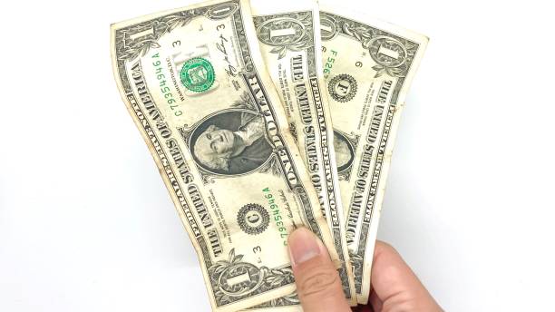 Hand of person holding 3 dollar bills