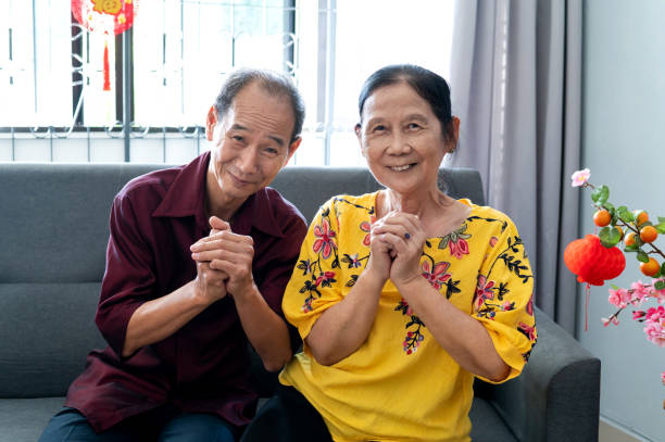 Happy smiling Asian grandparents celebrating Chinese New Year together at home Portrait of Asian Chinese grandparents celebrating Chinese New Year together in living room. They looking at camera and wishing everyone good wealth, good health and good prosperity through out the new year. grandmother real people front view head and shoulders stock pictures, royalty-free photos & images
