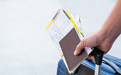Traveler man holding passports, map for travel with luggage for the trip, copy space for text.