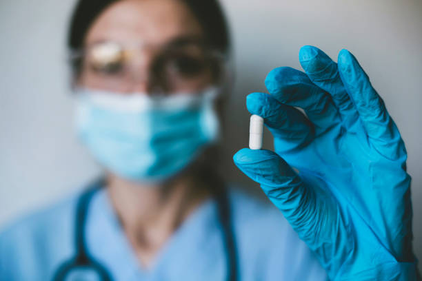 Infectious doctor holding COVID 19 antiviral drug Infectious doctor wearing protective workwear holding COVID 19 antiviral drug. Coronavirus pandemic. antiviral drug stock pictures, royalty-free photos & images