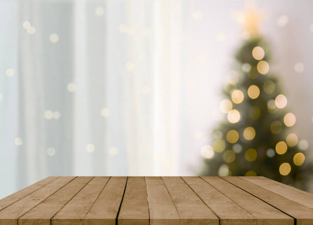 istock empty christmas table background with christmas tree out of focus for product display montage. 1355308348