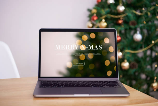 Mock up laptop computer on office table with Christmas tree and ornaments background. stock photo